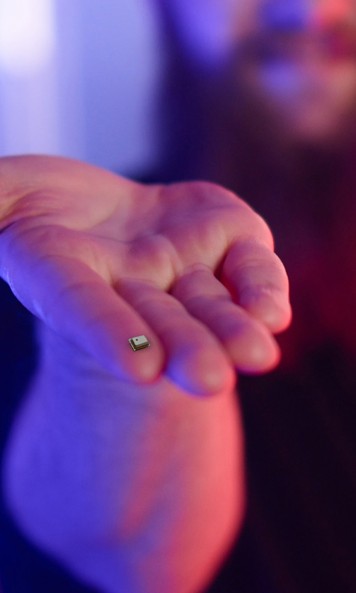 A hand holds a tiny sensor on his fingertip.